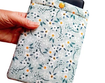 May include: A rectangular fabric sleeve featuring a light sage green background with a repeating pattern of white daisy flowers, yellow centers, and dark green foliage. The sleeve has a single yellow snap button closure at the top center.