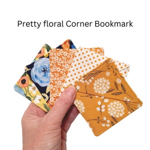 May include: Five fabric corner bookmarks with floral patterns. The bookmarks are in shades of yellow, white, blue, and orange.