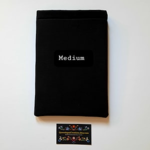 May include: A black fabric item with the word "Medium" on a black label. A business card with a floral design and the text "QueentopazCreations.Etsy.com Quality homemade face masks" is at the bottom.