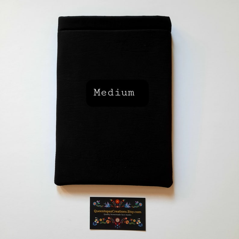 May include: A black fabric item with the word "Medium" on a black label. A business card with a floral design and the text "QueentopazCreations.Etsy.com Quality homemade face masks" is at the bottom.