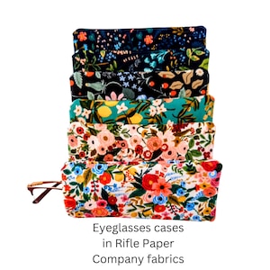 May include: A stack of five rectangular fabric eyeglasses cases featuring various floral and botanical patterns in colors including navy blue, teal, cream, pink, red, and orange. The text Eyeglasses cases in Rifle Paper Company fabrics is visible.
