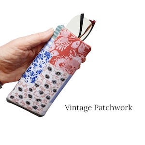 Pu&ograve; includere: Un astuccio per occhiali patchwork con motivi floreali e geometrici rossi, blu e bianchi. La custodia contiene un paio di occhiali. Il testo "Vintage Patchwork" &egrave; visualizzato in nero.
