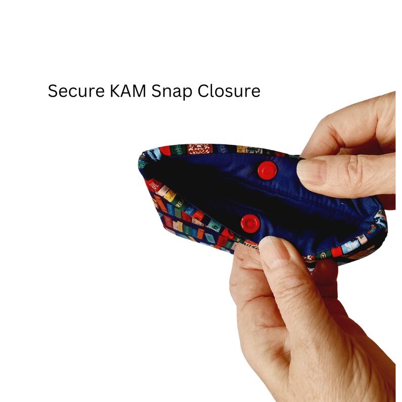May include: A blue fabric pouch with a colorful patterned design and two red snap closures. The pouch is open and the inside is lined with blue fabric. "Secure KAM Snap Closure" is written above the pouch.
