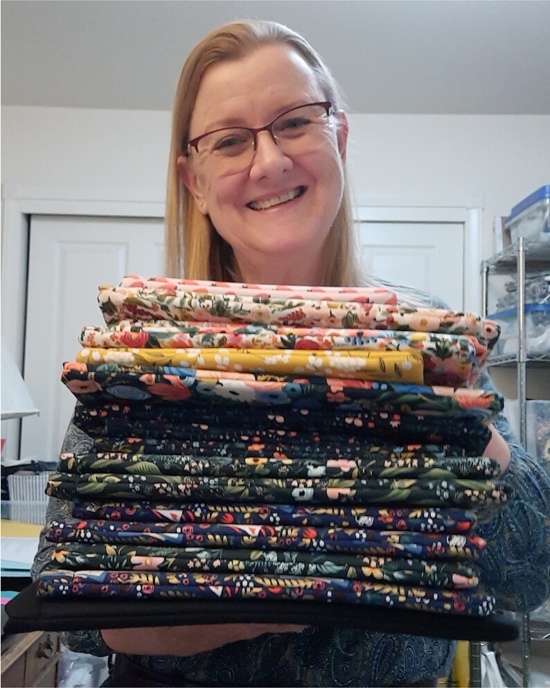 May include: A stack of colorful fabric with floral patterns. The fabric is folded and stacked neatly. The fabric is in various shades of blue, green, yellow, pink, and white.