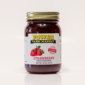 May include: A glass jar of Fowl's Farm Market strawberry fruit preserves. The jar has a gold lid and a white label with red strawberries and the text "All Natural". The net weight is 20 ounces (567 grams).