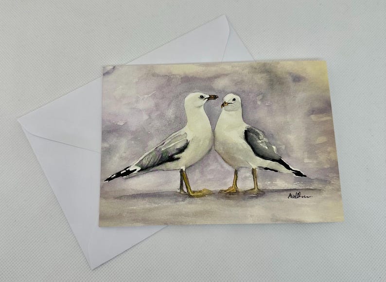 Watercolour print painting of two seagulls facing each other on a purple background. The seagulls are white with grey wings and black markings.