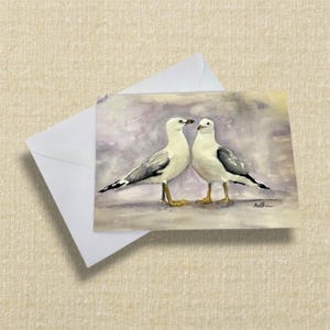 greeting card featuring two seagulls stood next to each other with tonal purple background. printed from my original watercolour painting.