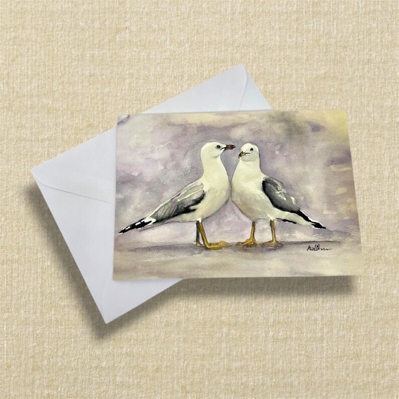 greeting card featuring two seagulls stood next to each other with tonal purple background. printed from my original watercolour painting.