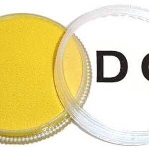 Op de afbeelding: Een ronde verpakking met gele verf en een doorzichtig deksel. Het deksel heeft de letters "DC" erop gedrukt.