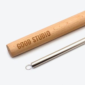 May include: A wooden stirring stick with the words "GOOD STUDIO" engraved on it, and a silver metal straw with a loop at the end.