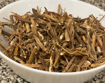 May include: A white ceramic bowl filled with dried, brown, and tan plant stems. The stems have a fibrous texture and vary in thickness and length. The bowl is set against a speckled, gray and white countertop.