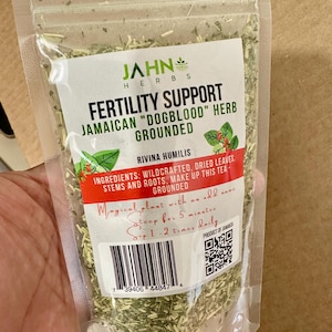 Puede incluir: Una bolsa de plástico transparente con hierba Dogblood jamaicana seca y molida, etiquetada como Fertility Support de Jahn Herbs. La etiqueta muestra texto verde, una franja roja, un código de barras y un código QR con los ingredientes.