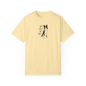 Puede incluir: Camiseta amarillo claro con una ilustraci&oacute;n en blanco y negro de un perro y el texto "ARE YOU UP YET?". El perro est&aacute; representado sentado. La camiseta tiene mangas cortas y cuello redondo.