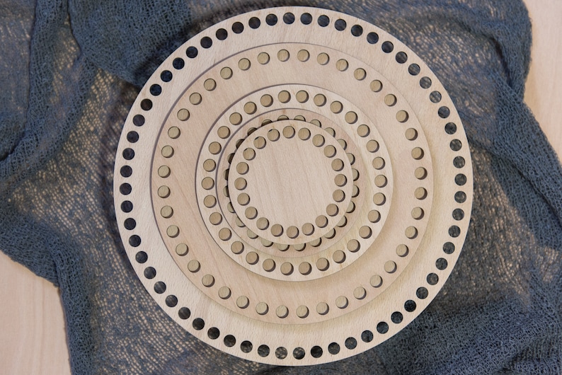 K&ouml;nnte beinhalten: Satz mit vier runden Holz-H&auml;kelringen, die ineinander gesteckt sind. Die Ringe sind aus Naturholz gefertigt und haben eine glatte Oberfl&auml;che. Der gr&ouml;&szlig;te Ring hat einen Durchmesser von etwa 30 cm.