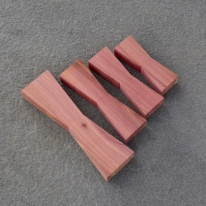 May include: Four wooden bow tie shapes made of cedar wood, arranged in a pyramid shape on a gray textured surface.