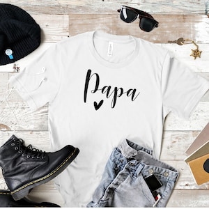 May include: White t-shirt with the word "Papa" written in black cursive with a small black heart underneath.