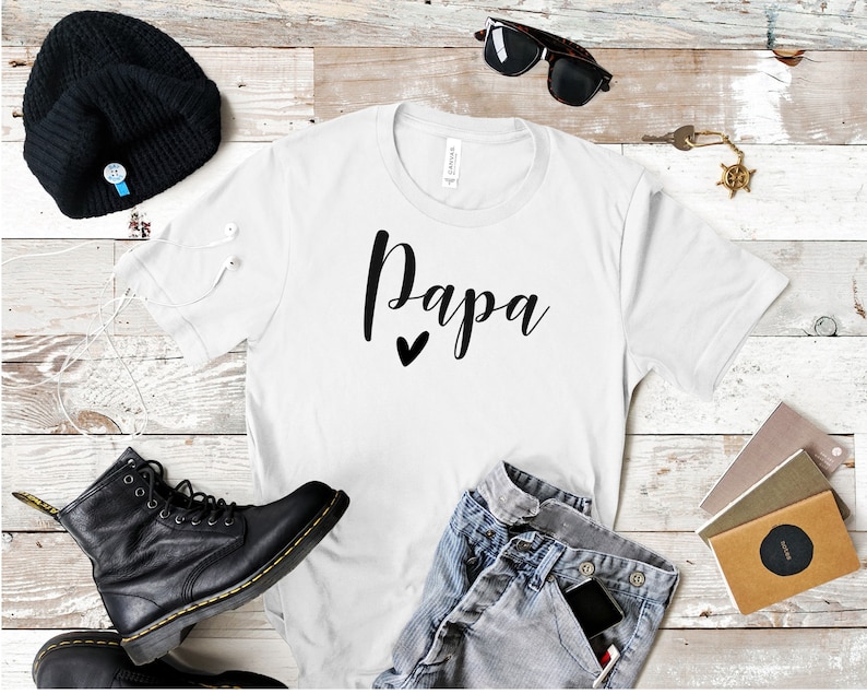 May include: White t-shirt with the word "Papa" written in black cursive with a small black heart underneath.