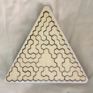 May include: A wooden triangle puzzle with a geometric pattern of hexagons. The puzzle is made of light wood and has a dark brown outline.