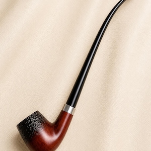 May include: A long-stemmed tobacco pipe featuring a smooth, reddish-brown wooden bowl with a textured, dark-stained top rim. The pipe includes a slender, curved black stem connected to the bowl by a polished silver-colored metal band.