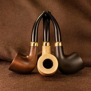 May include: Three wooden smoking pipes with black and gold accents. The pipes are arranged in a triangle shape with the bowl of each pipe facing the viewer.