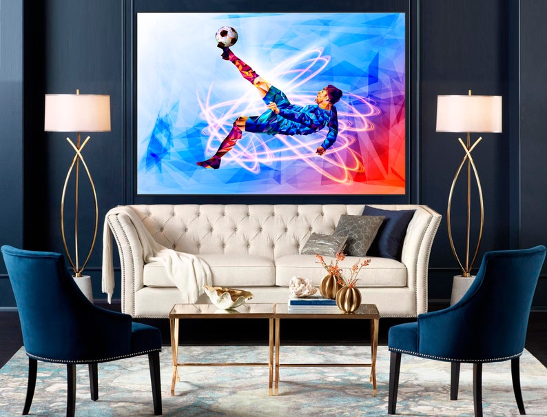 May include: A white sofa with a white throw blanket and two blue armchairs in a living room with a large abstract painting of a soccer player kicking a ball. The painting has a blue, red, and white color scheme.