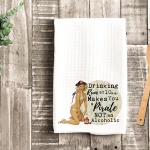 Op de afbeelding: Witte keukendoek met een kleurrijke illustratie van een vrouw in bikini die een fles rum vasthoudt. De tekst luidt "Drinking Rum at 10 a.m. Makes You a Pirate NOT an Alcoholic".