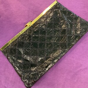 May include: A black snakeskin clutch bag with a gold clasp.