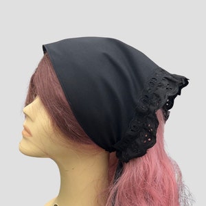 Puede incluir: Un pa&ntilde;uelo de algod&oacute;n negro con ribete de encaje negro. El pa&ntilde;uelo est&aacute; atado alrededor de la cabeza de un maniqu&iacute; con cabello rosado.