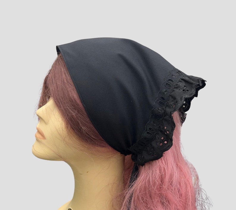 Puede incluir: Un pa&ntilde;uelo de algod&oacute;n negro con ribete de encaje negro. El pa&ntilde;uelo est&aacute; atado alrededor de la cabeza de un maniqu&iacute; con cabello rosado.