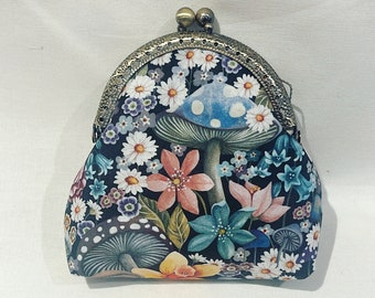 May include: A small, black coin purse with a floral and mushroom print. The purse has a brass clasp and a rounded shape.