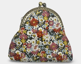 May include: A coin purse featuring a black fabric base with a dense, multi-colored floral pattern of white, red, pink, yellow, and light blue daisies. The purse has an arched, antique-style brass metal frame with a kiss-lock clasp closure.