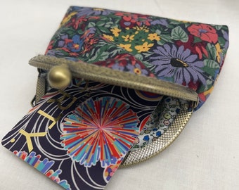 May include: A small floral print coin purse with a brass clasp and a colorful tag that says "Lily" in gold lettering.