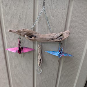 Gru origami graziose e uniche nel loro genere su un acchiappasole in legno galleggiante
