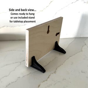 Pode incluir: Vista lateral e traseira de uma placa de madeira com um suporte preto. A placa est&aacute; pronta para ser pendurada ou colocada em uma mesa. O texto na placa diz "Side and back view... Comes ready to hang or use included stand for tabletop placement."