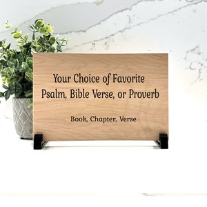Pode incluir: Uma placa de madeira com o texto "Your Choice of Favorite Psalm, Bible Verse, or Proverb Book, Chapter, Verse" gravado nela.