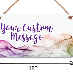 May include: A white rectangular sign with a purple, pink, and green abstract design. The sign has a rope for hanging and the text "Your Custom Message" in purple lettering.