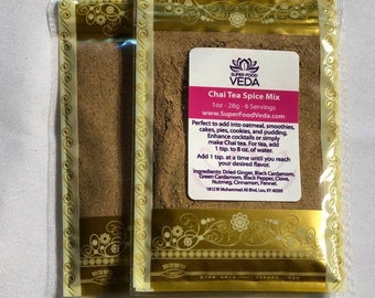 May include: A small, gold-trimmed pouch containing a brown spice mix. The pouch has a label that reads "Super Food Veda Chai Tea Spice Mix 1oz - 28g - 6 Servings www.SuperFoodVeda.com". The label also lists the ingredients: Dried Ginger, Black Cardamom, Green Cardamom, Black Pepper, Clove, Nutmeg, Cinnamon, Fennel.