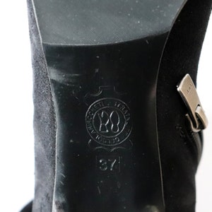 May include: Close-up of a black suede boot with a zipper and a leather sole. The sole features a circular emblem with the number 20 and the size 37.