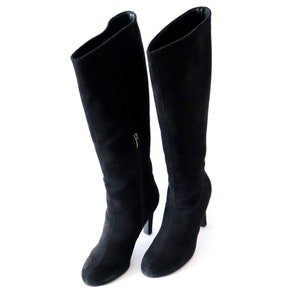 May include: A pair of black suede knee-high boots. The boots have a pointed toe, a zipper on the side, and a stiletto heel. The boots are approximately 30 inches tall.