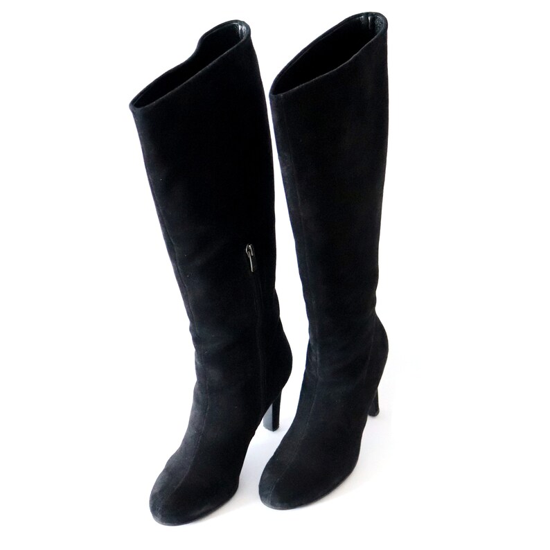 May include: A pair of black suede knee-high boots. The boots have a pointed toe, a zipper on the side, and a stiletto heel. The boots are approximately 30 inches tall.