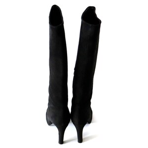May include: A pair of black knee-high boots with stiletto heels. The boots are made of a soft, suede-like material and have a sleek, minimalist design. The heels are approximately 3 inches (7.6 cm) high.
