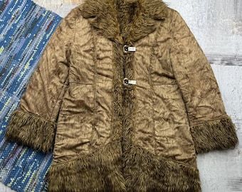 May include: A brown faux fur coat with a brown faux fur collar and cuffs. The coat has a button closure and a slightly flared hem.