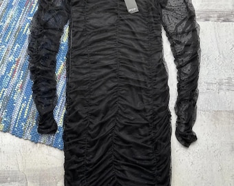 May include: Black long-sleeved dress with a polka dot pattern. The dress is made of a sheer fabric and has a ruched design.