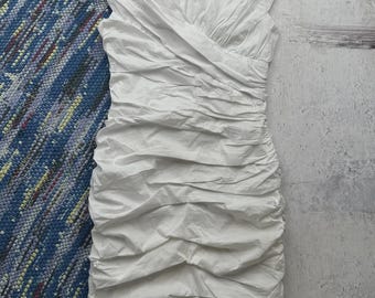 May include: A white, short-sleeved dress with a V-neckline and a ruched design. The dress is made of a lightweight fabric and has a fitted silhouette.
