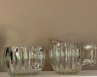 Peut inclure: Un ensemble sucrier et crémier en verre transparent avec un motif côtelé. Le pot à crème a une poignée.