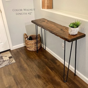 Puede incluir: Una mesa consola de madera de nogal con patas de horquilla negras. La mesa tiene 42 pulgadas (106,68 cm) de largo. La mesa est&aacute; en un ambiente hogare&ntilde;o con una cesta y una planta en maceta en la parte superior.