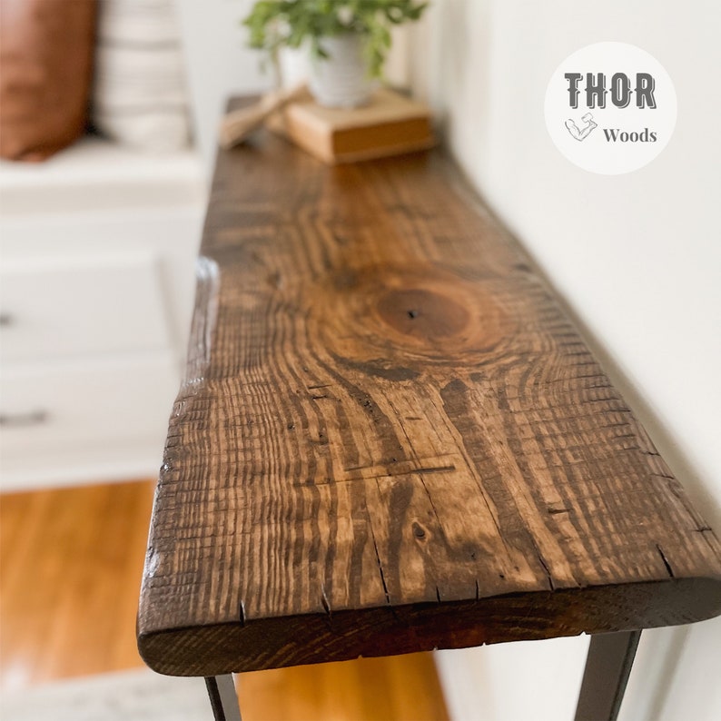 May include: A dark brown wooden console table with a live edge top and black metal legs. The table is sitting on a wooden floor. The text "THOR Woods" is visible in the upper right corner of the image.