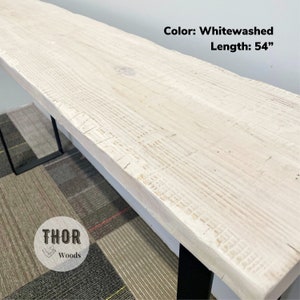 May include: Whitewashed wood table top with black metal legs. The table is 54 inches long. The table is made by THOR Woods.