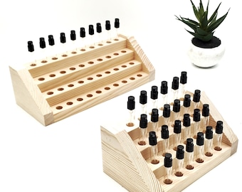 May include: Two wooden display stands with rows of small glass bottles with black spray tops. The stands are made of light wood and have a tiered design. The bottles are arranged in rows on the stands.