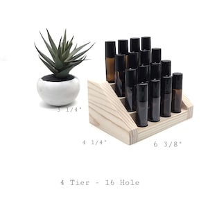 May include: A wooden, 4-tier display stand with 16 holes, holding several amber and black roller bottles. The stand measures 6 3/8 inches wide, 4 1/4 inches deep. A small succulent in a white pot is to the left. The text reads: 4 Tier - 16 Hole.